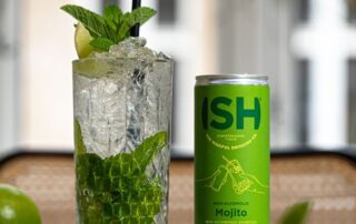 Refreshing mojito drink with fresh mint and lime beside a green ISH can.