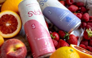 Two cans of Slade sparkling water surrounded by fresh fruits.