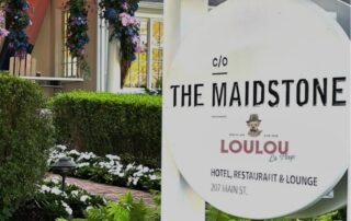 Sign for The Maidstone hotel and restaurant with lush greenery around.