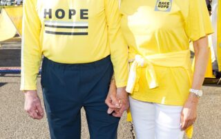 Two people holding hands wearing yellow shirts with hope messages.