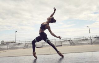 Dancer in mid-leap outdoors, showcasing grace and strength.