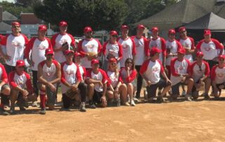 A youth baseball team posing together on the field in red and white uniforms.