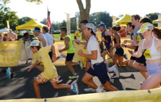 A group of runners racing outdoors on a sunny day.