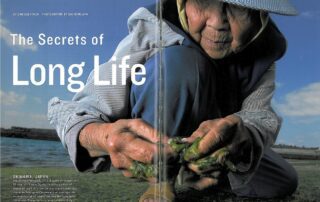 An elderly person in a hooded jacket working with seaweed.