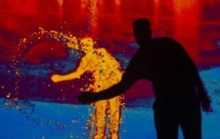 Silhouetted person interacting with vibrant, colorful digital art.