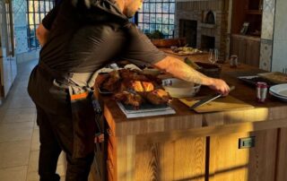 A man serving food in a warmly lit kitchen with wooden decor.