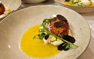Gourmet dish with seared scallop, creamy sauce, and truffle slices.
