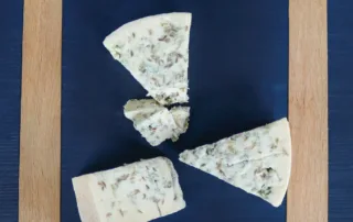 Pieces of blue cheese on a dark board with a wooden frame.