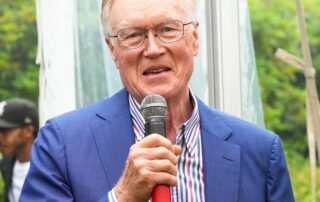 Man in blue suit speaks into a microphone.