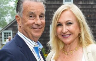 A smiling older couple posing outdoors in formal attire.