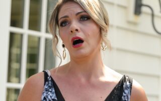 Woman in black dress singing outdoors.