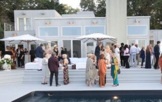 People socializing at a modern outdoor pool party during the day.