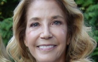Smiling middle-aged woman with blonde hair outdoors.