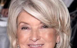 Smiling elderly woman with short blonde hair and earrings.