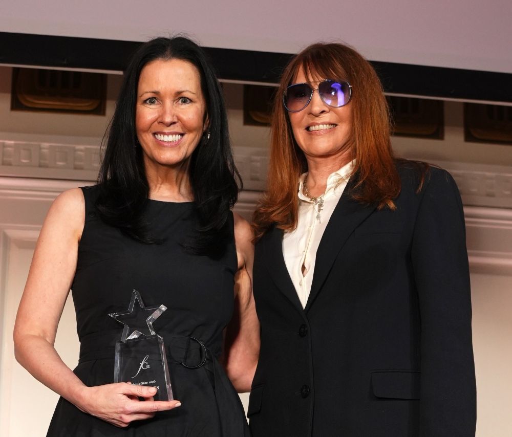Two women smiling, one holding a star-shaped award.