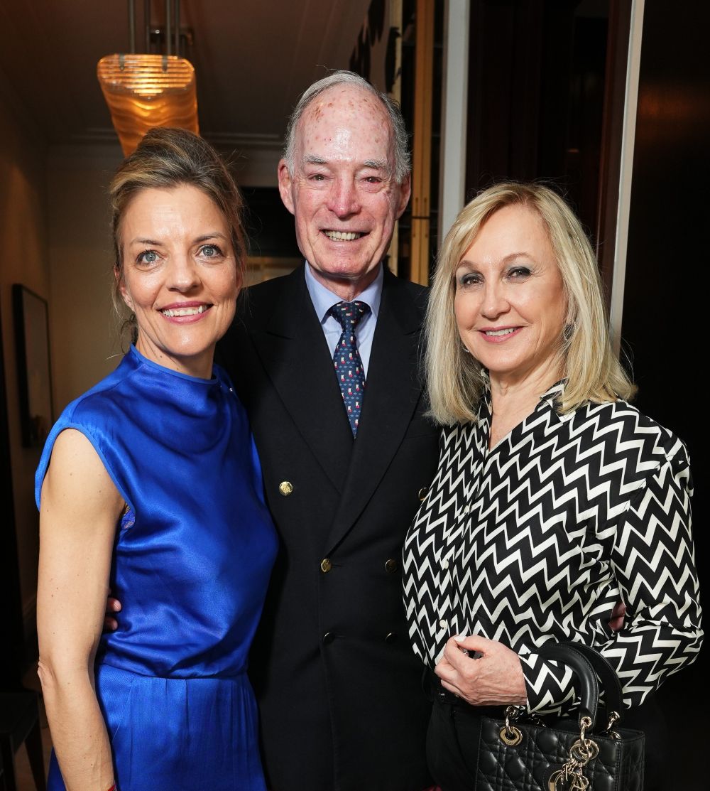 Three people posing happily at an indoor event.