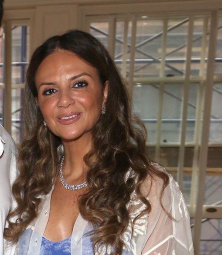 Woman with long brown hair, wearing white top.