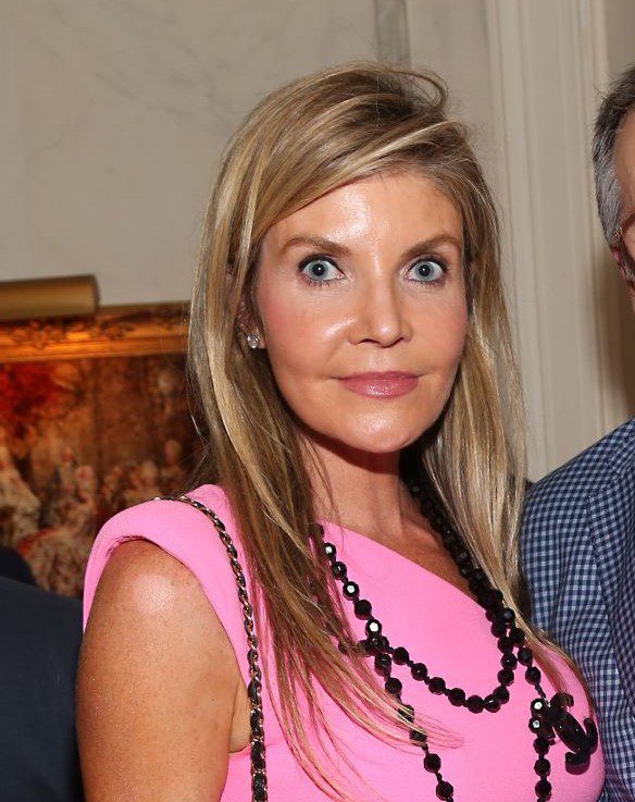 Woman in pink dress with black necklace.