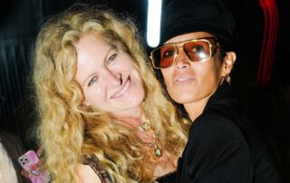 Two women smiling at a night event.