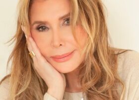 Portrait of a woman with long blonde hair resting her face on her hand.