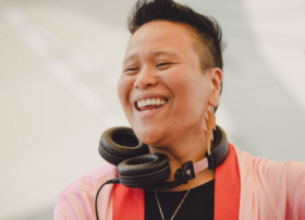 Smiling person with headphones around their neck enjoying a moment.