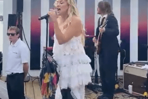 Here's an alt tag for the image: Singer performing on stage with band.