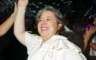 Woman in white top dancing at party.