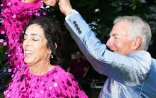 An elderly couple joyfully dancing outdoors.