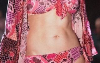 Here's an alt tag for the image: Woman in pink floral bikini and sheer cover-up.