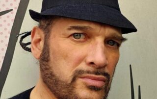 Here's an alt tag for the image: Man in hat, serious expression.
