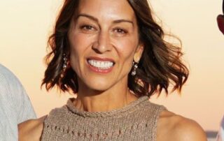Smiling woman in beige knit top.