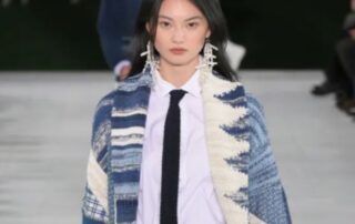 Model in blue patterned cardigan and tie.