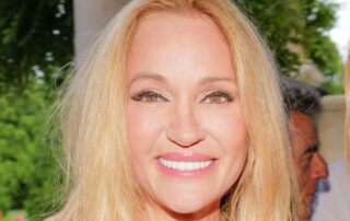 Smiling woman with long blonde hair outdoors in natural light.