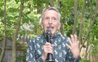 Elderly man speaking passionately into a microphone outdoors.