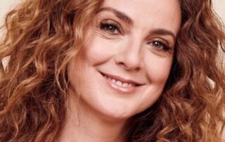 Close-up portrait of a smiling woman with curly hair.