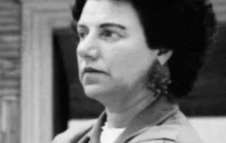 Black and white photo of a serious woman with curly hair and large earrings.
