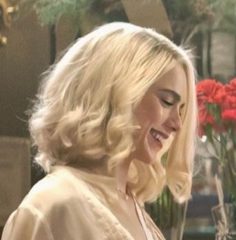 Smiling woman with blonde wavy hair in a soft-lit setting.