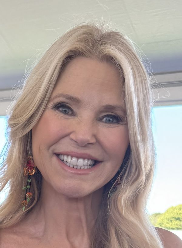 Smiling woman with blonde hair and colorful earrings.