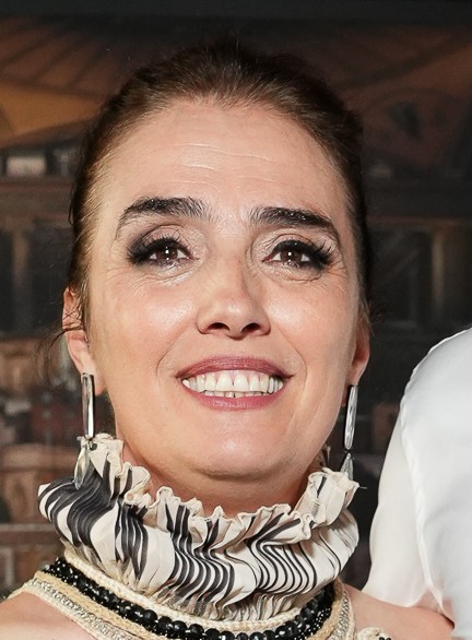 Close-up of a smiling woman with elegant makeup and earrings.