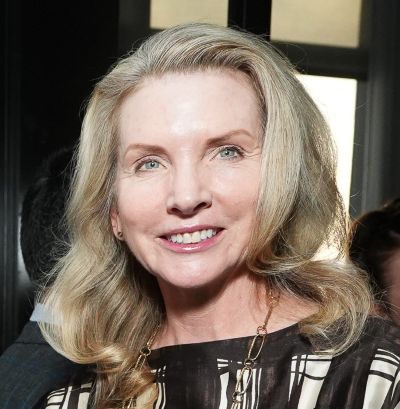 Smiling woman with blonde hair at an indoor event.
