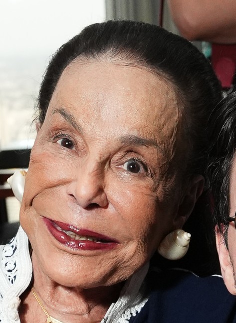 Close-up of an elderly woman smiling warmly at the camera.
